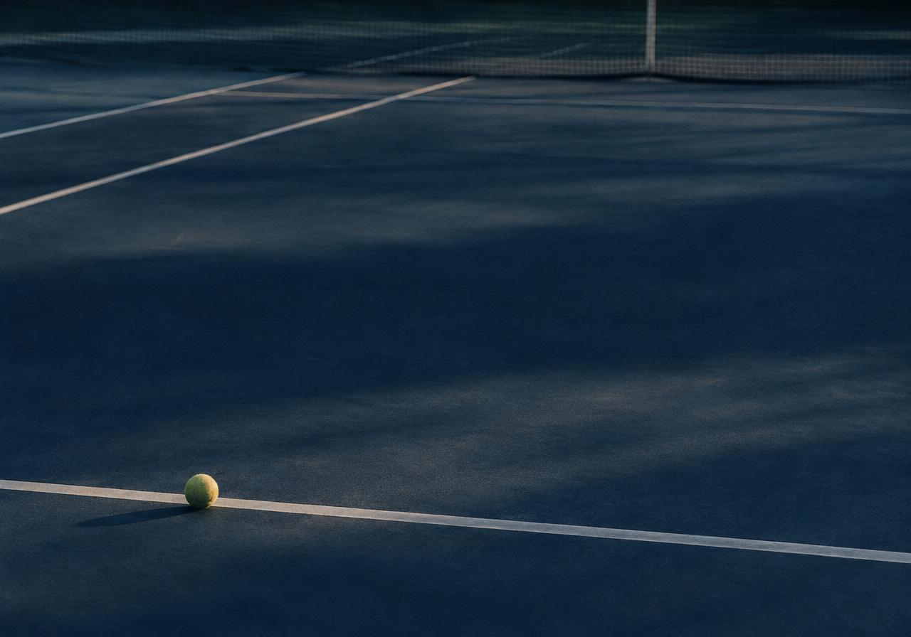 Quadra de tênis ao amanhecer, com uma bola sobre a linha de fundo